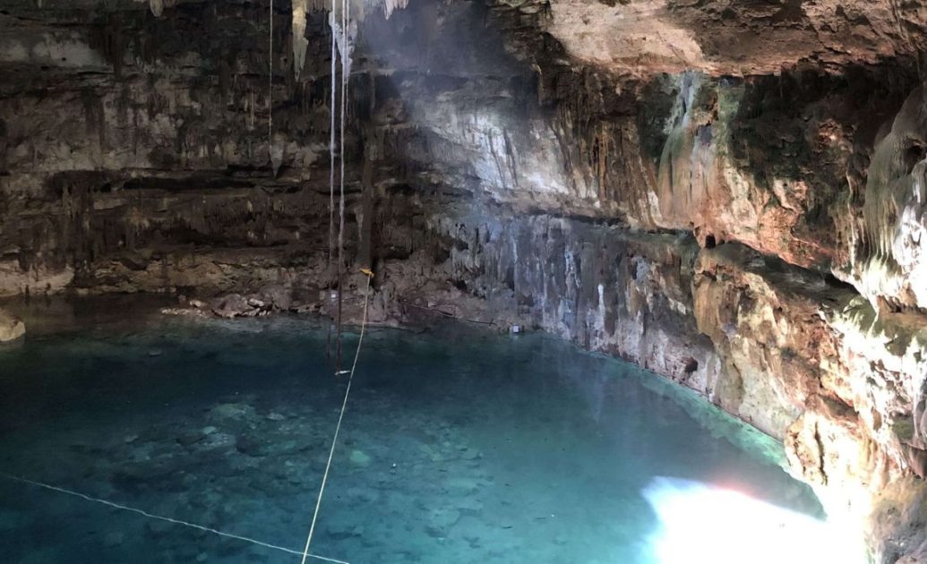Cenote in Mexico with blue water and beam of light