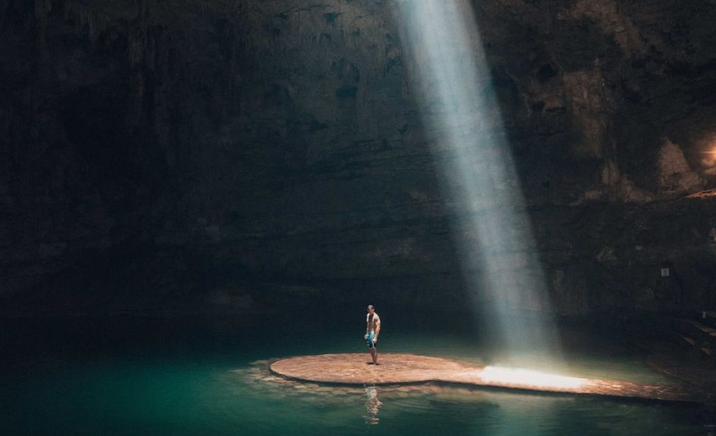 Photo of man standing in cave surrounded by water