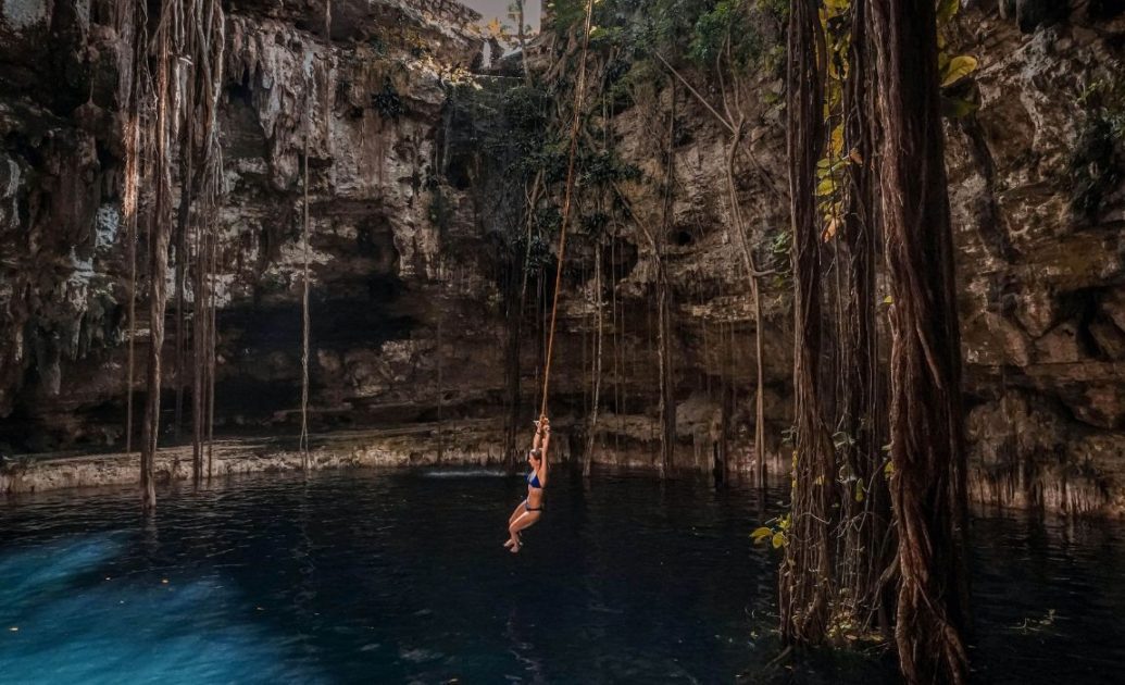 Woman swinging from rope into body of water